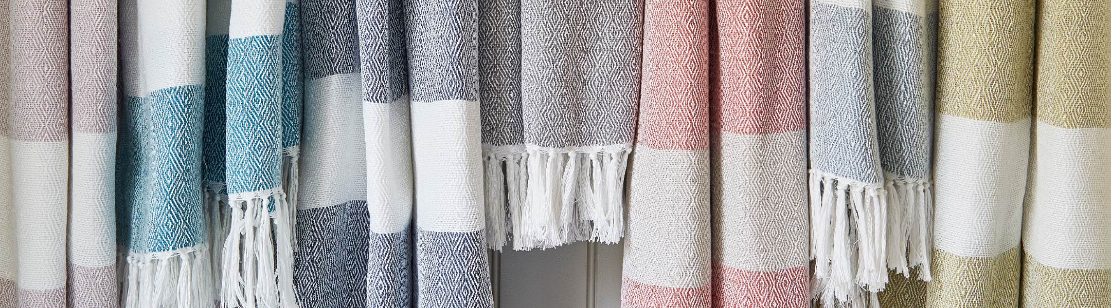 Brightly coloured hammam throws hung up against a wood panelled wall.