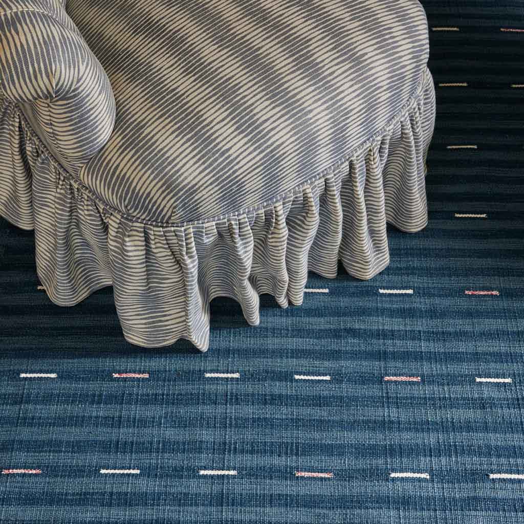 Textured blue carpet with a striped fabric item on top