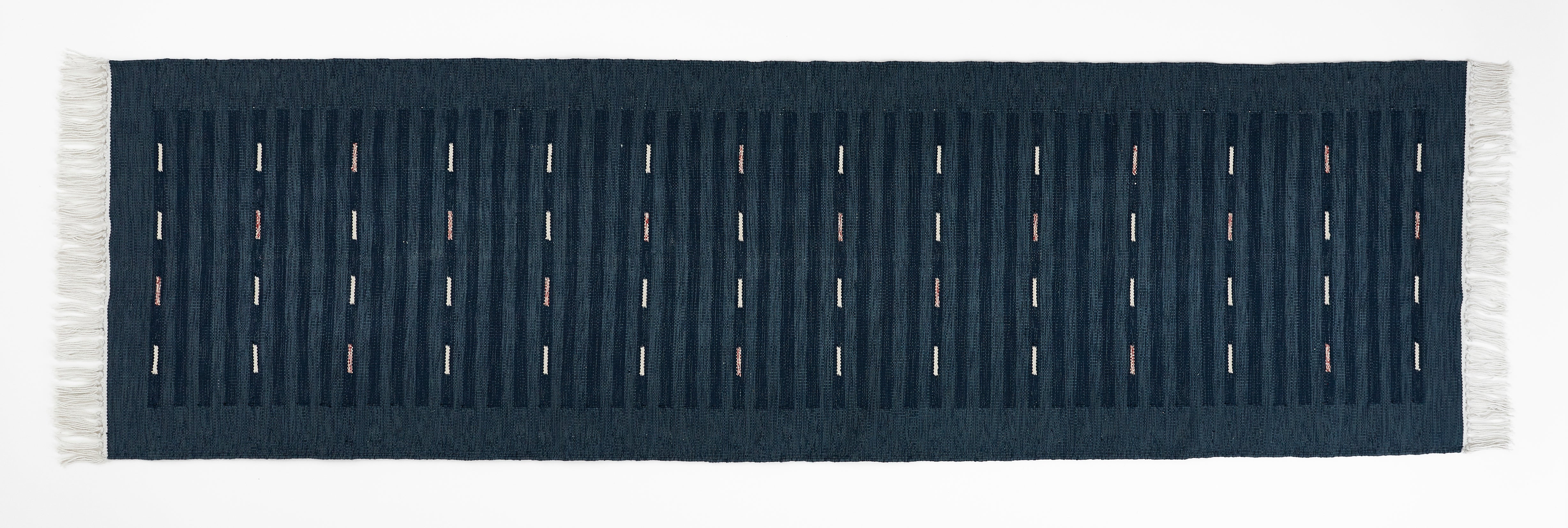 Navy blue runner rug with white fringe on a plain background