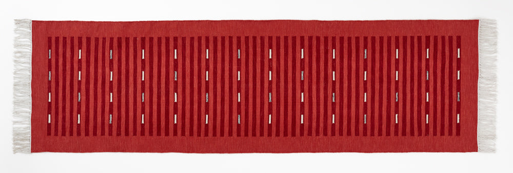 Red runner rug with white fringe on a white background