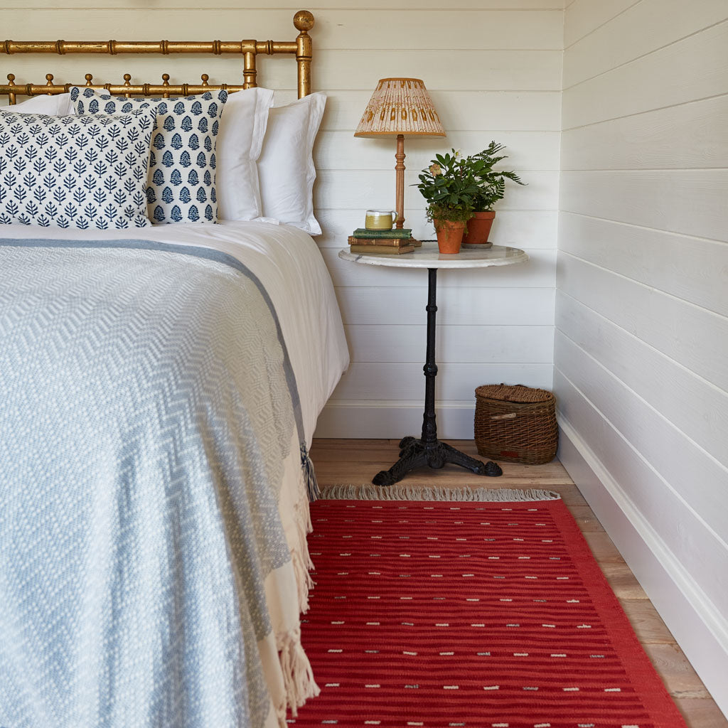 Red striped rug next to a bed