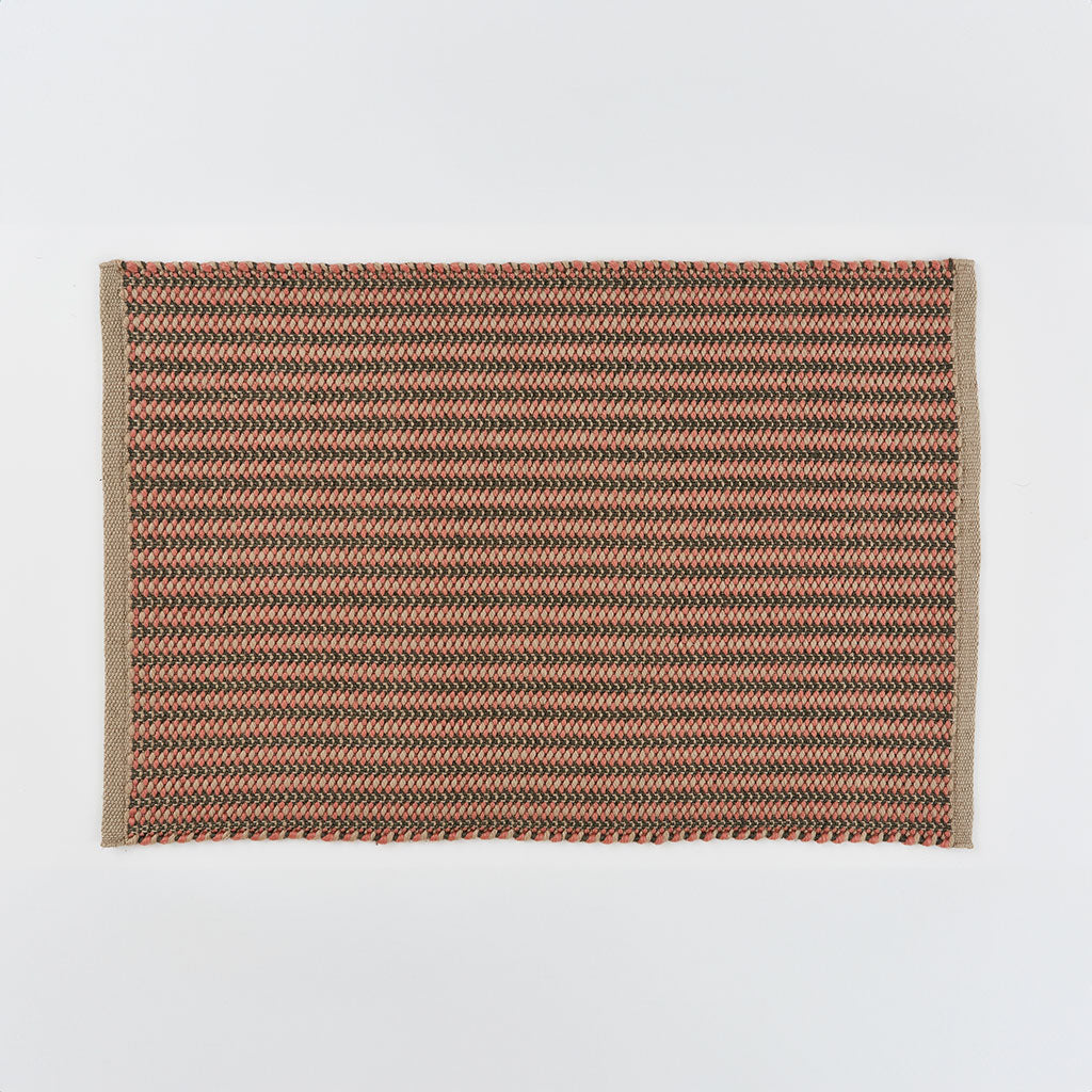 A hand-woven rug with a striped pattern in coral and charcoal colors