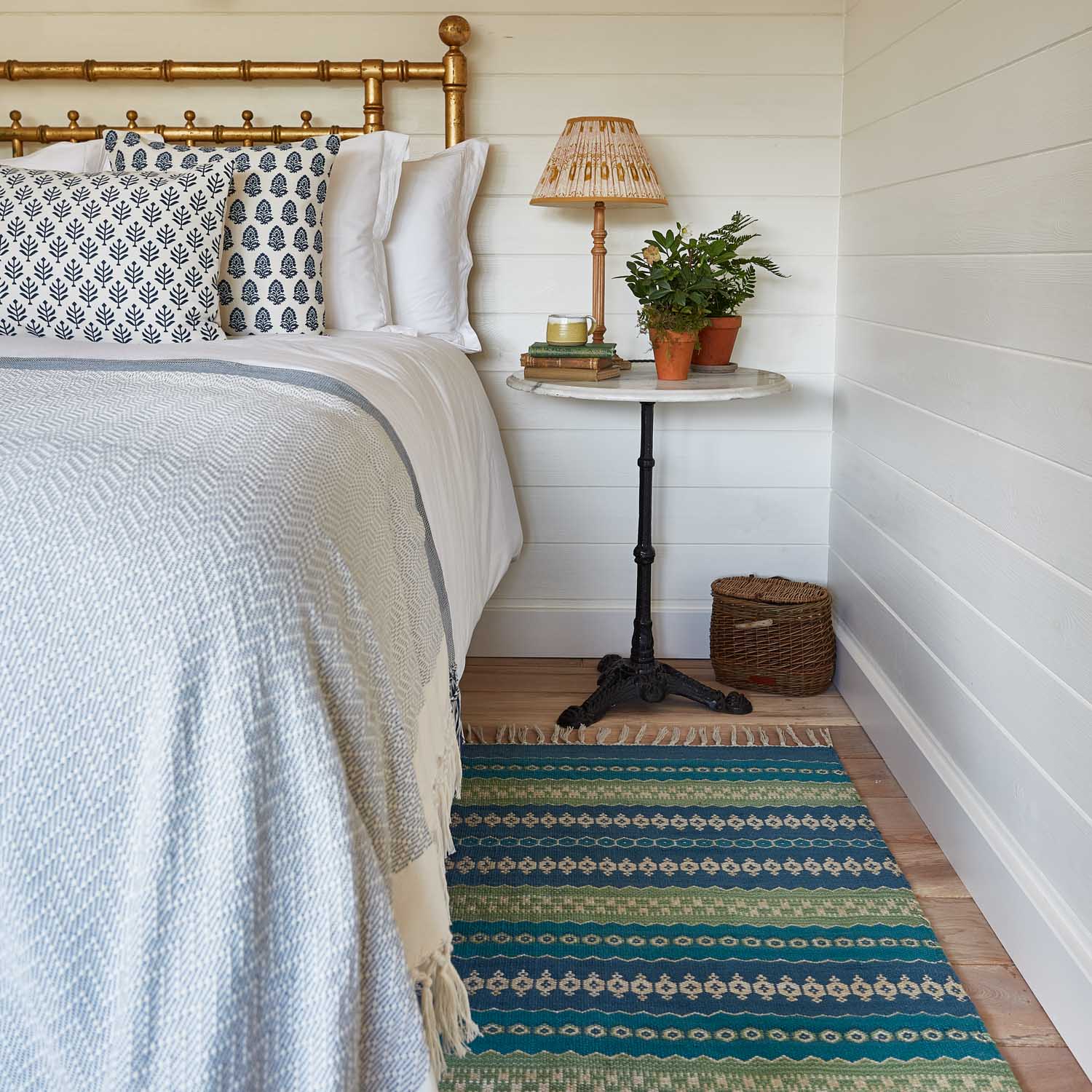 A colorful striped rug with green and blue stripes next to a bed