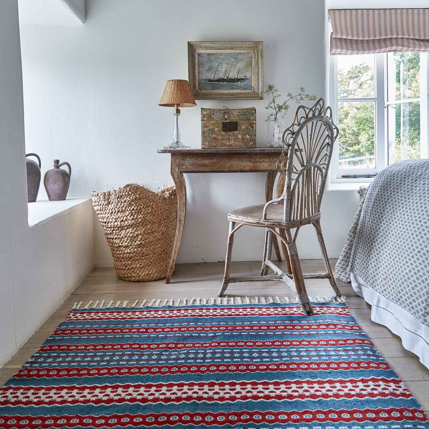 A red and blue striped rug with a geometric pattern in a bedroom