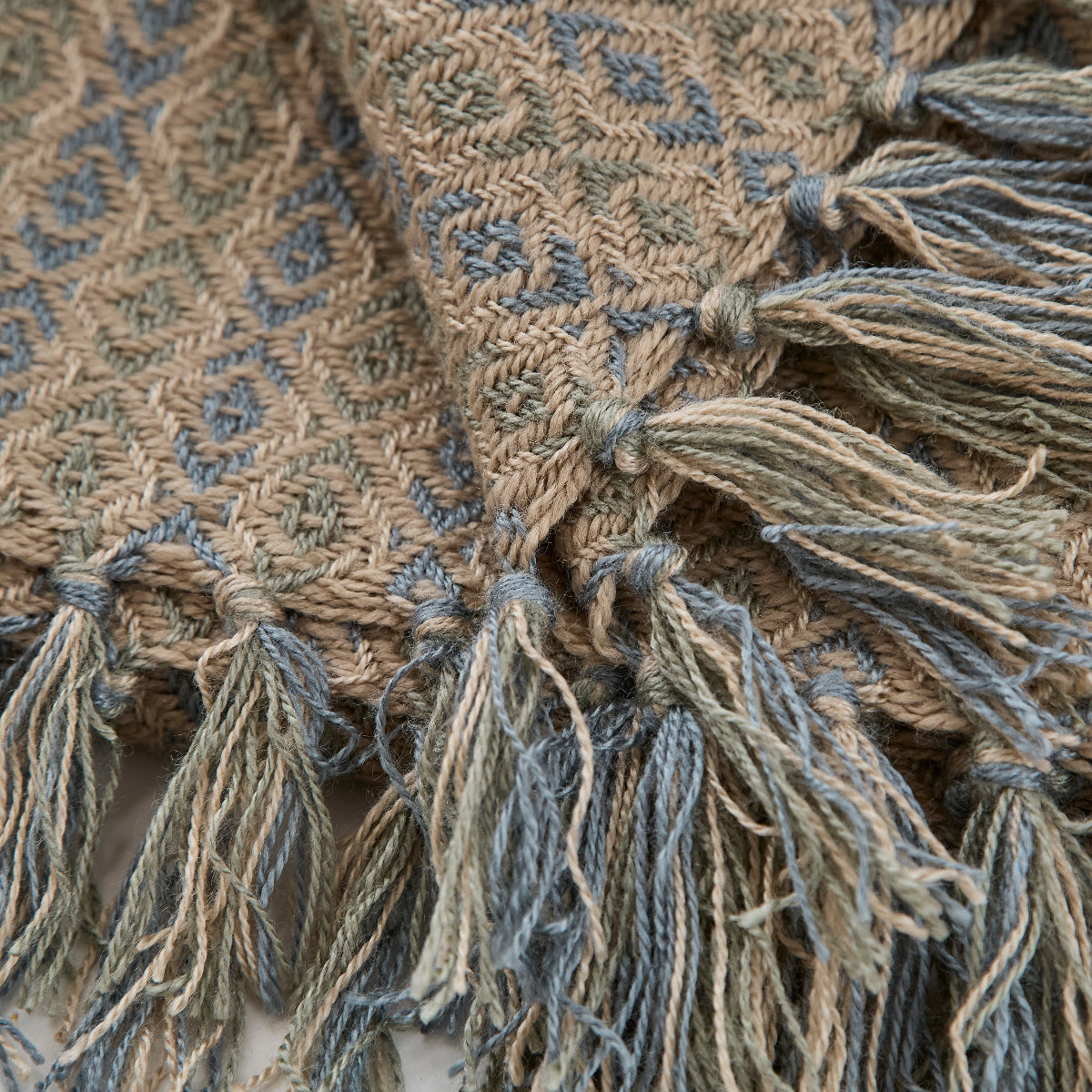 Close-up of a textured fabric with tassels and intricate patterns.