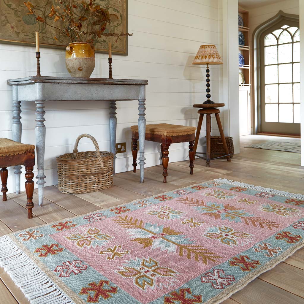 A pink, pale blue and neutral coloured rug in the hallway