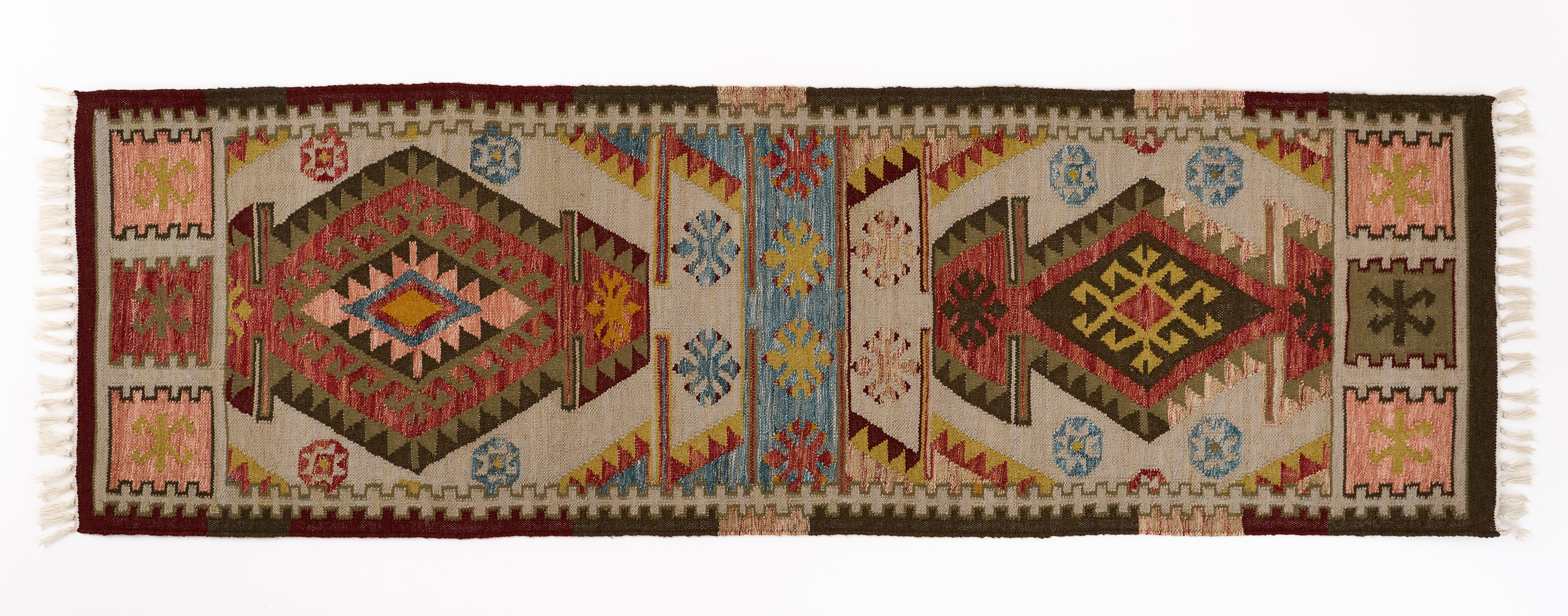 Runner rug in soft umber, burnt orange, faded blues and earthy saffron tones with geometric pattern on a plain background.