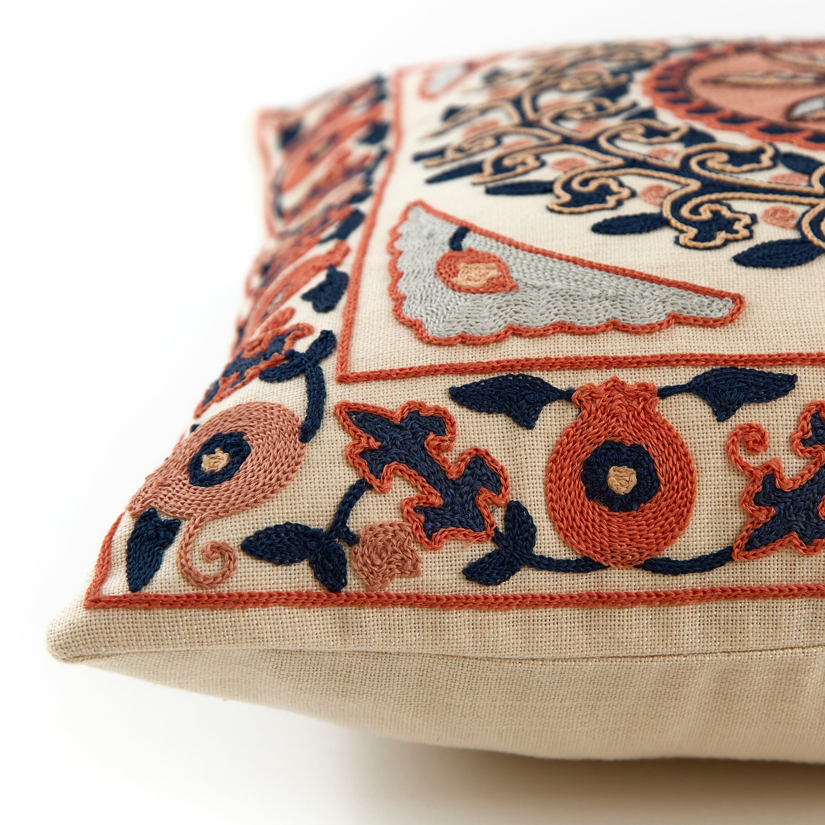 Close up image of embroidered cushion in coral and navy floral design.