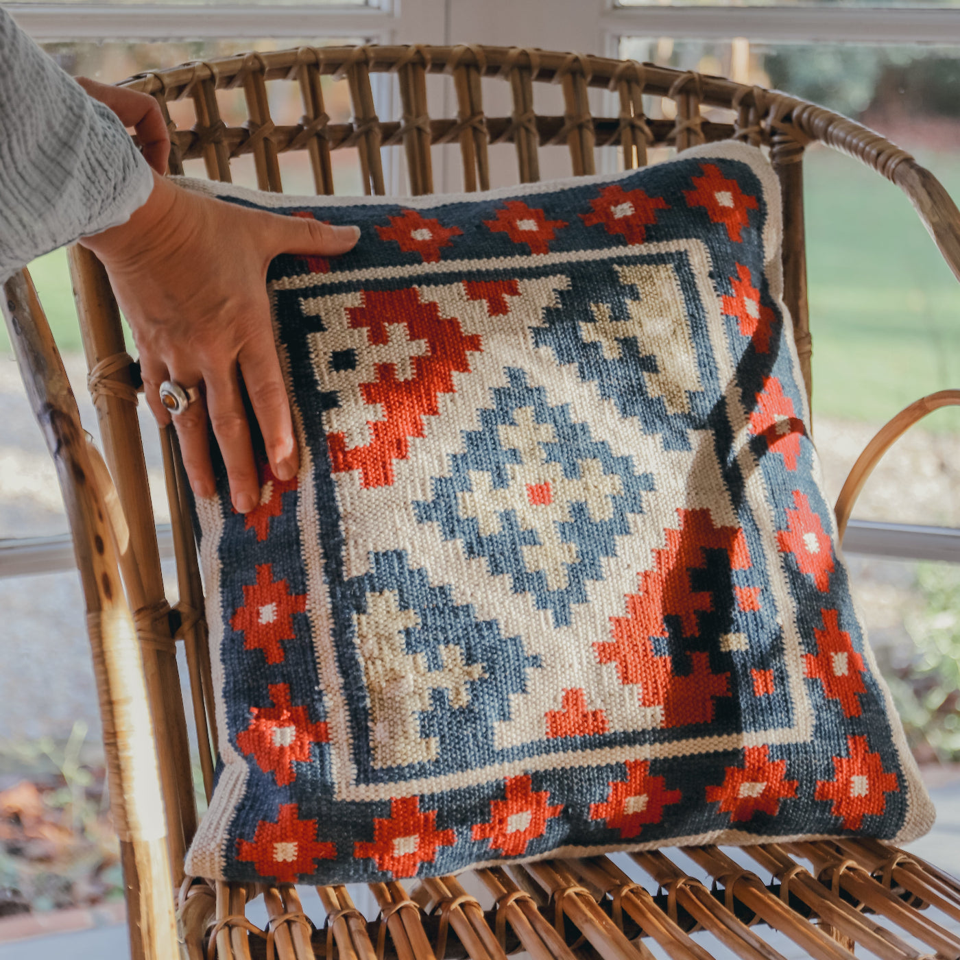 Decorative pillow with geometric pattern on a wicker chair