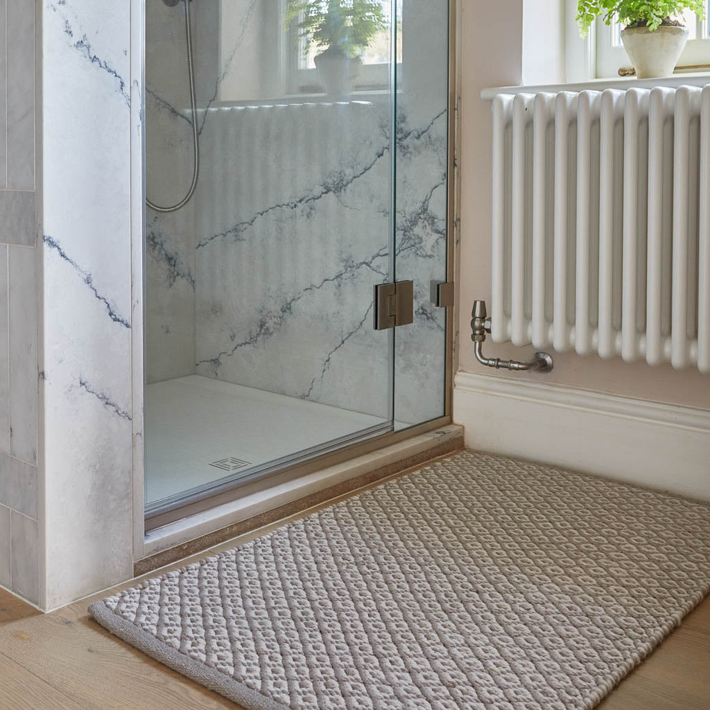 A gray rug with diamond geometric pattern placed on a floor, likely in a home environment.