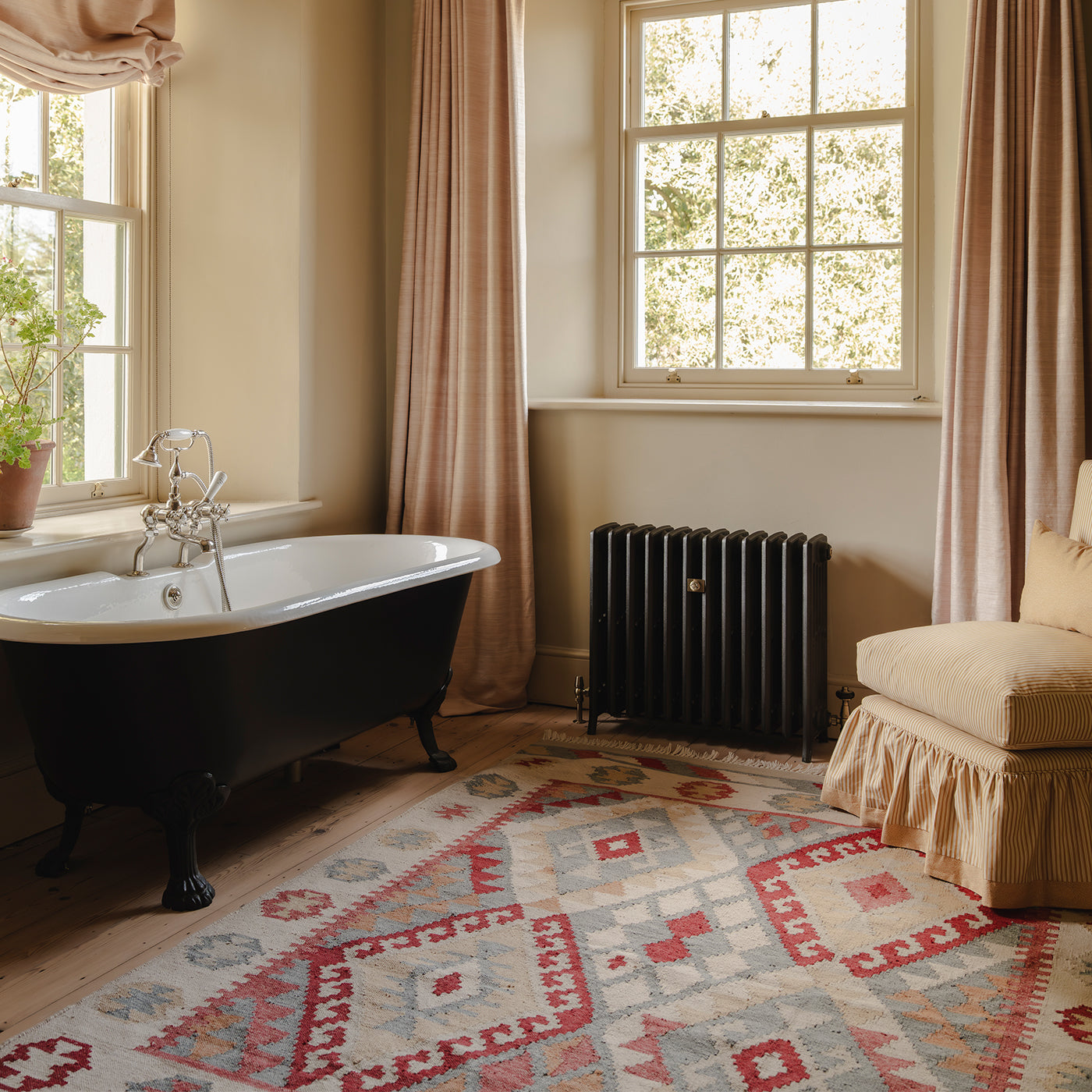 Bathroom with a freestanding bathtub, radiator, and patterned Asman kilim rug. *collection_bathroom-rugs