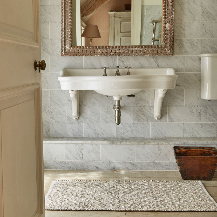 bathmat underneath a sink and mirror in the bathroom