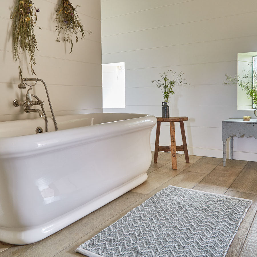 dove grey bathmat in bathroom next to roll top bath
