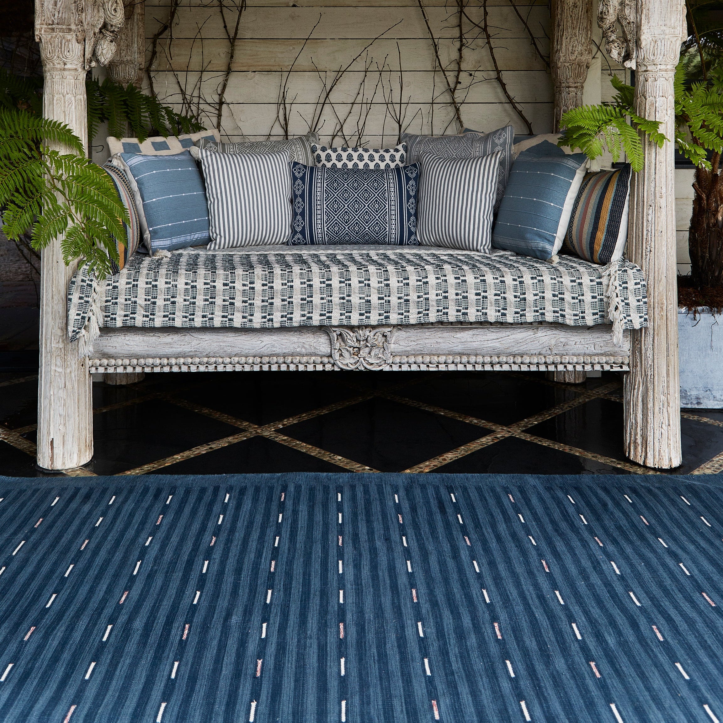 Decorative outdoor swing with cushions against a brick wall