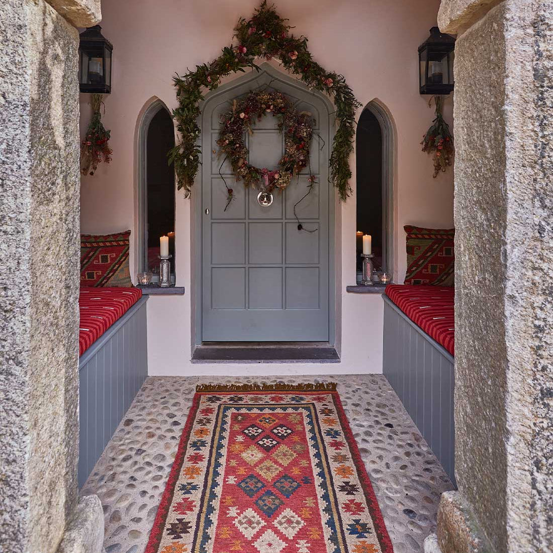 Decorative entrance with wreath, candles, and patterned rug.
