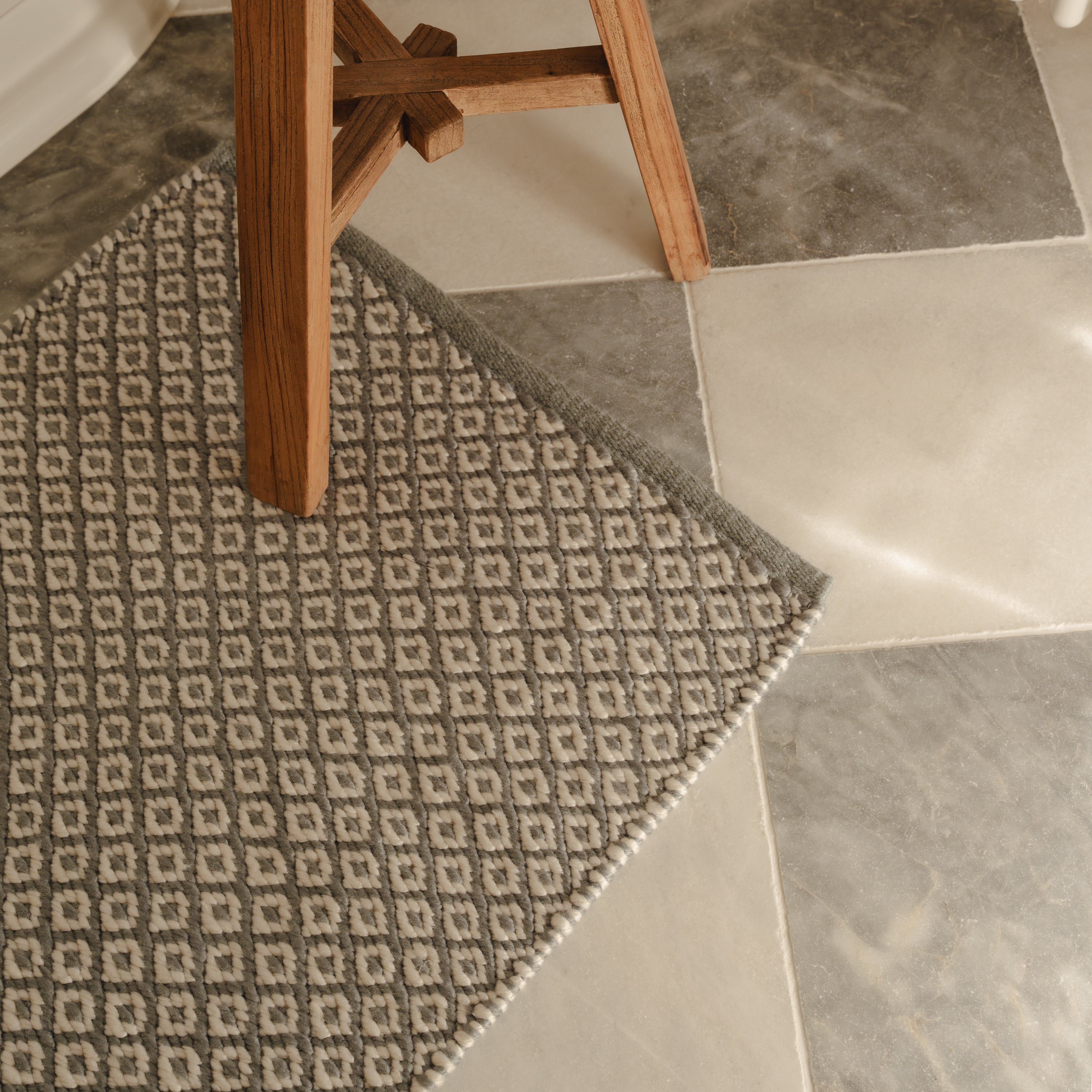 Wooden stool on a patterned rug with tiled floor