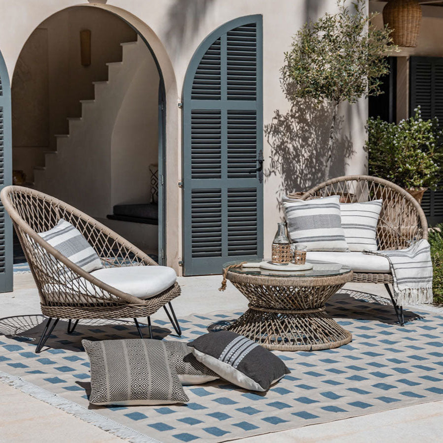 Outdoor patio setting with wicker furniture, cushions, and a small table.