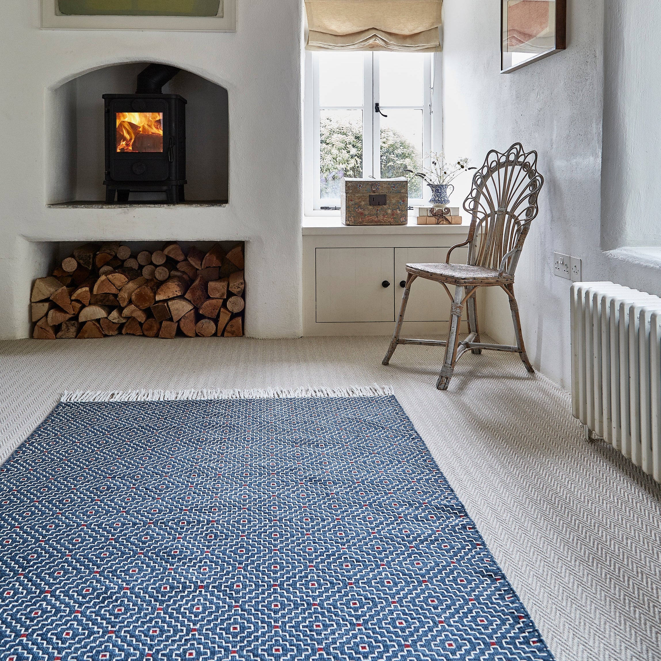 Cozy living room with a fireplace, wooden chair, and blue patterned rug.