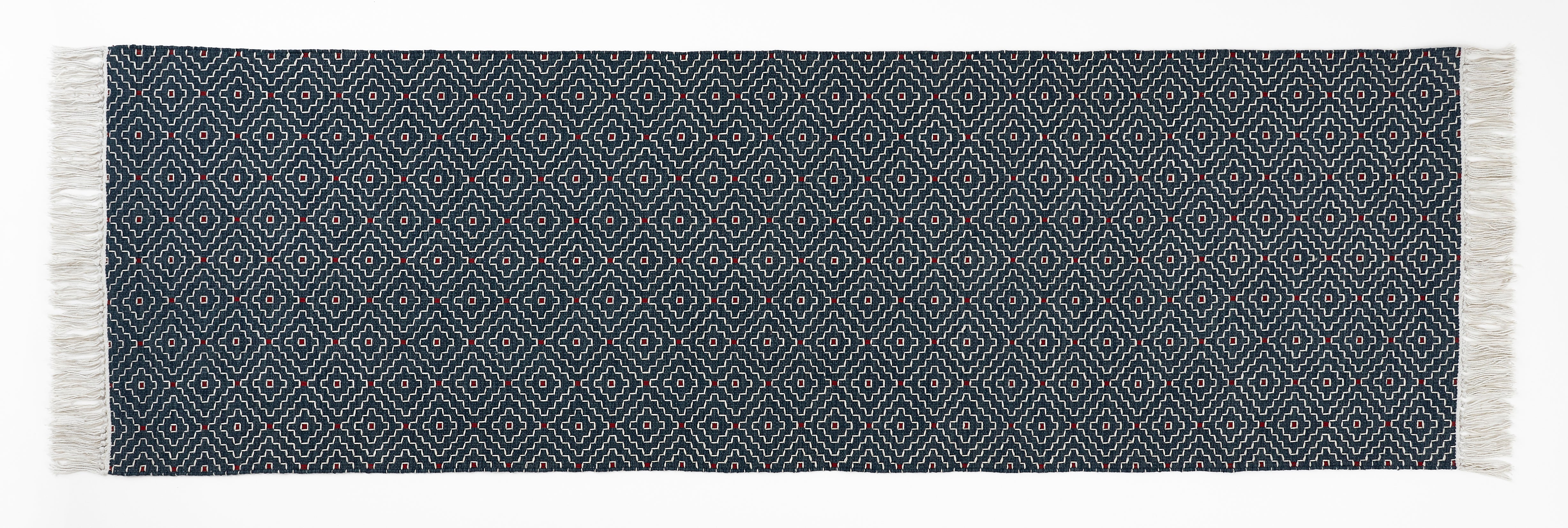 Navy blue woven runner with white geometric pattern and fringes on a white background