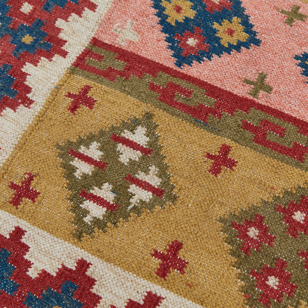 Geometric patterned rug in blue pink red and olive colourways