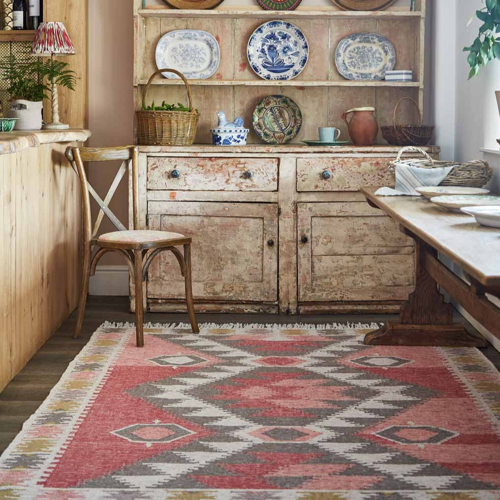 A geometric colourful rug in the kitchen with a dresser and chair.