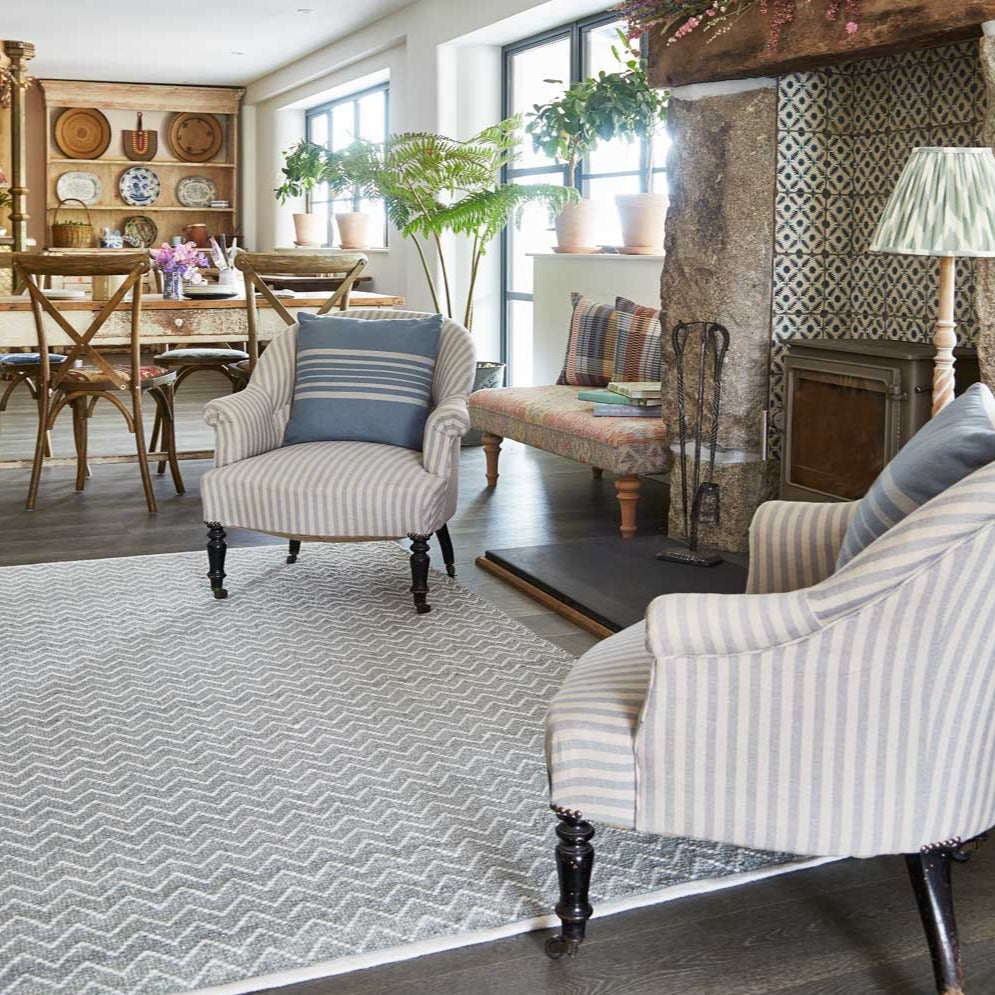 a dove grey herringbone rug in a living room next to a fireplace