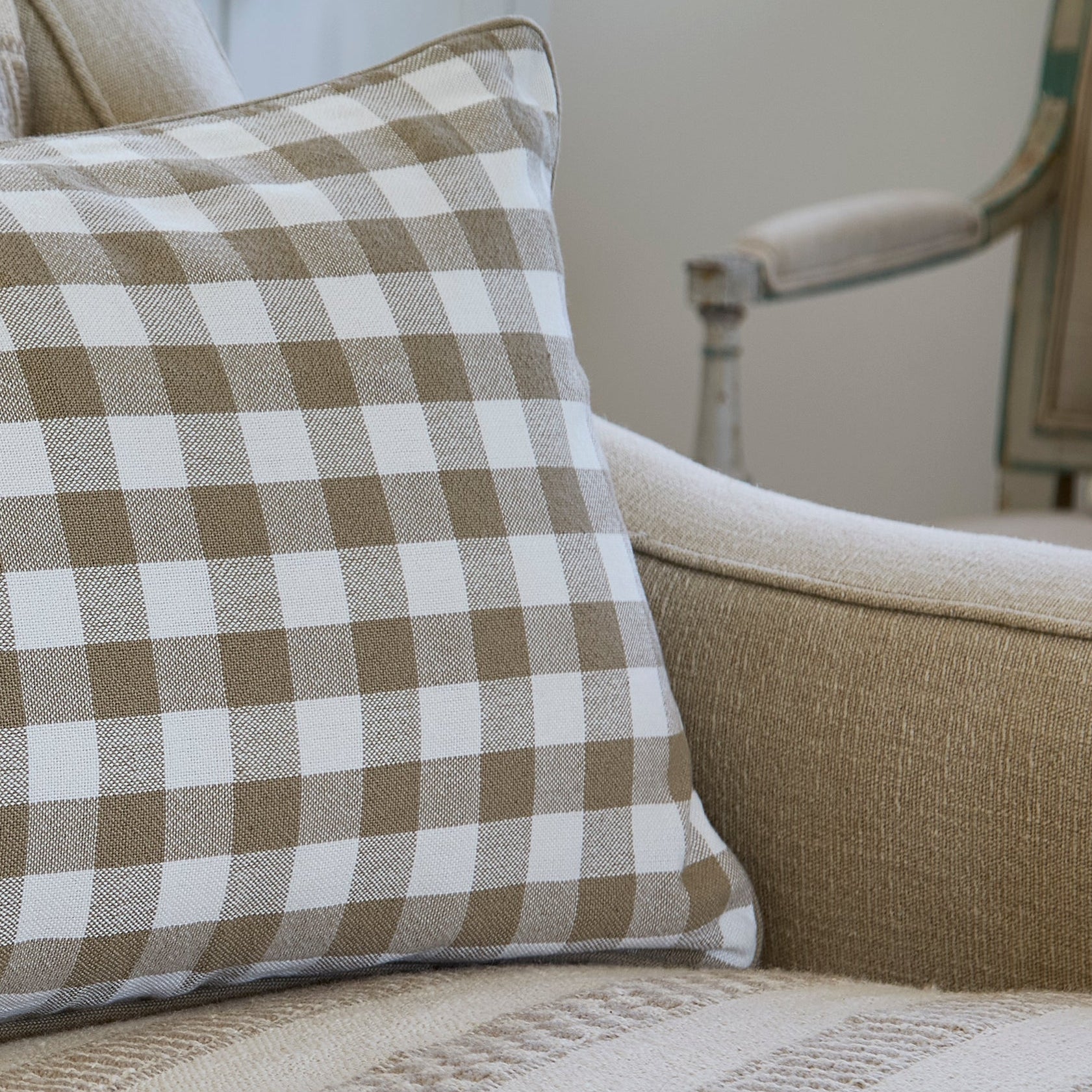 Checkered pillow on a patterned sofa with another chair in the background.