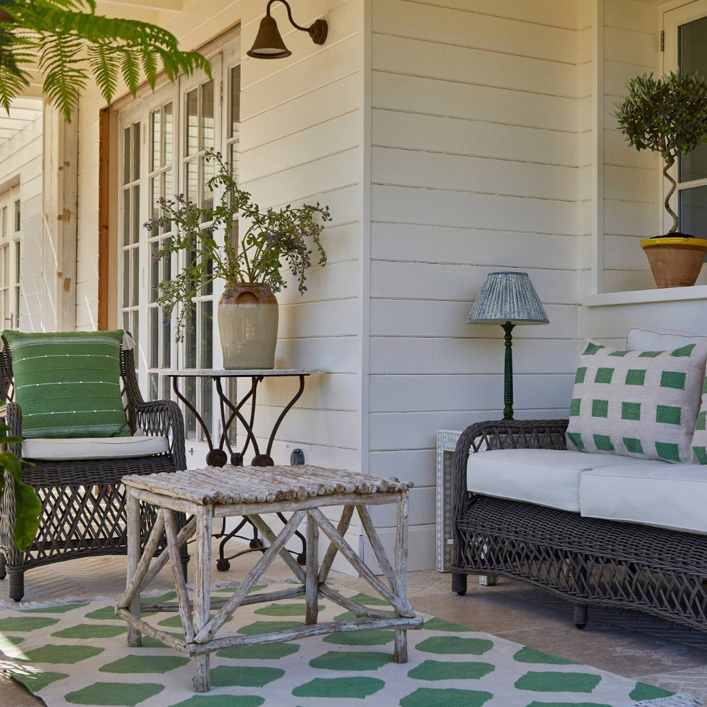 Outdoor patio with wicker furniture, table, and decorative elements on a porch.