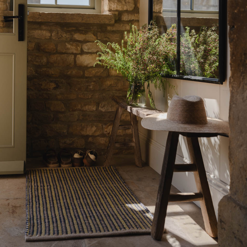 Nook with stone wall, wooden stool, and plants in a rustic setting