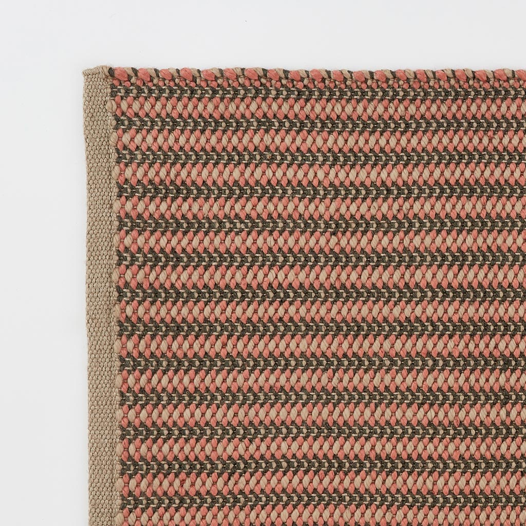 A hand-woven rug with a striped pattern in coral and charcoal colors
