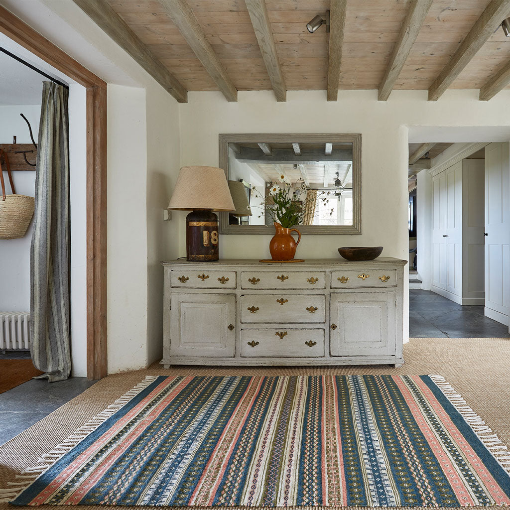 a blue, coral and olive striped rug in a hallway 