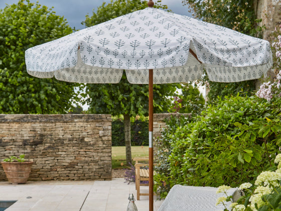 Outdoor patio parasol with floral pattern in a garden setting. 
