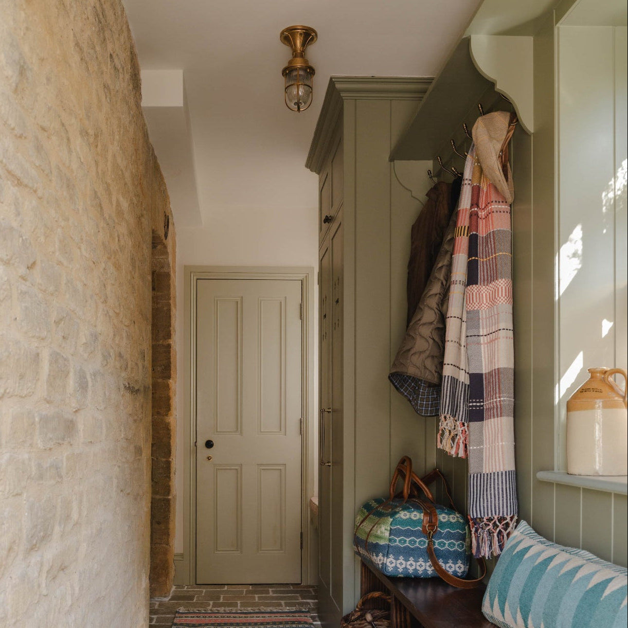Narrow hallway with stone walls, wooden bench, and Weaver Green Check Throw.