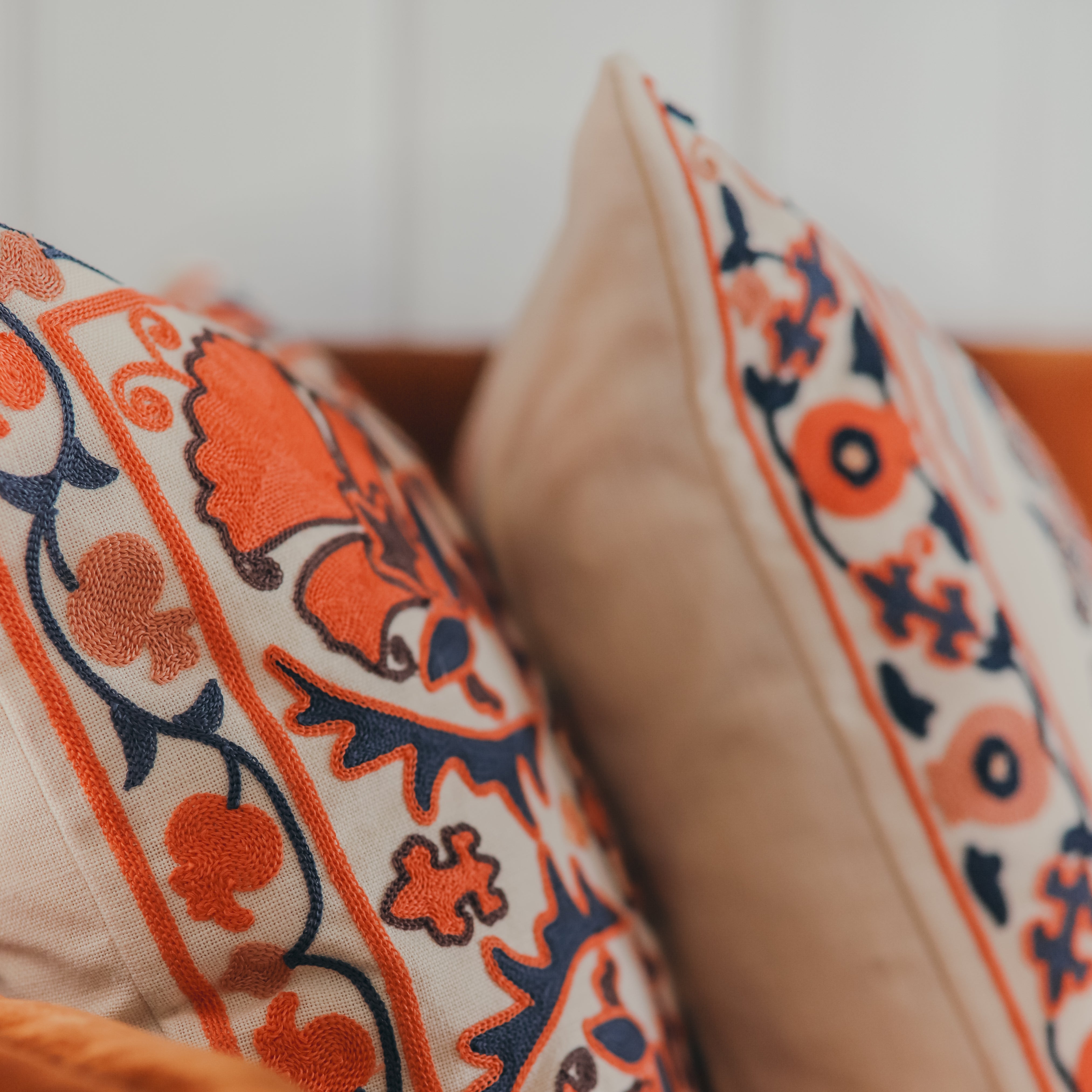 Embroidered cushion with coral and navy floral design.