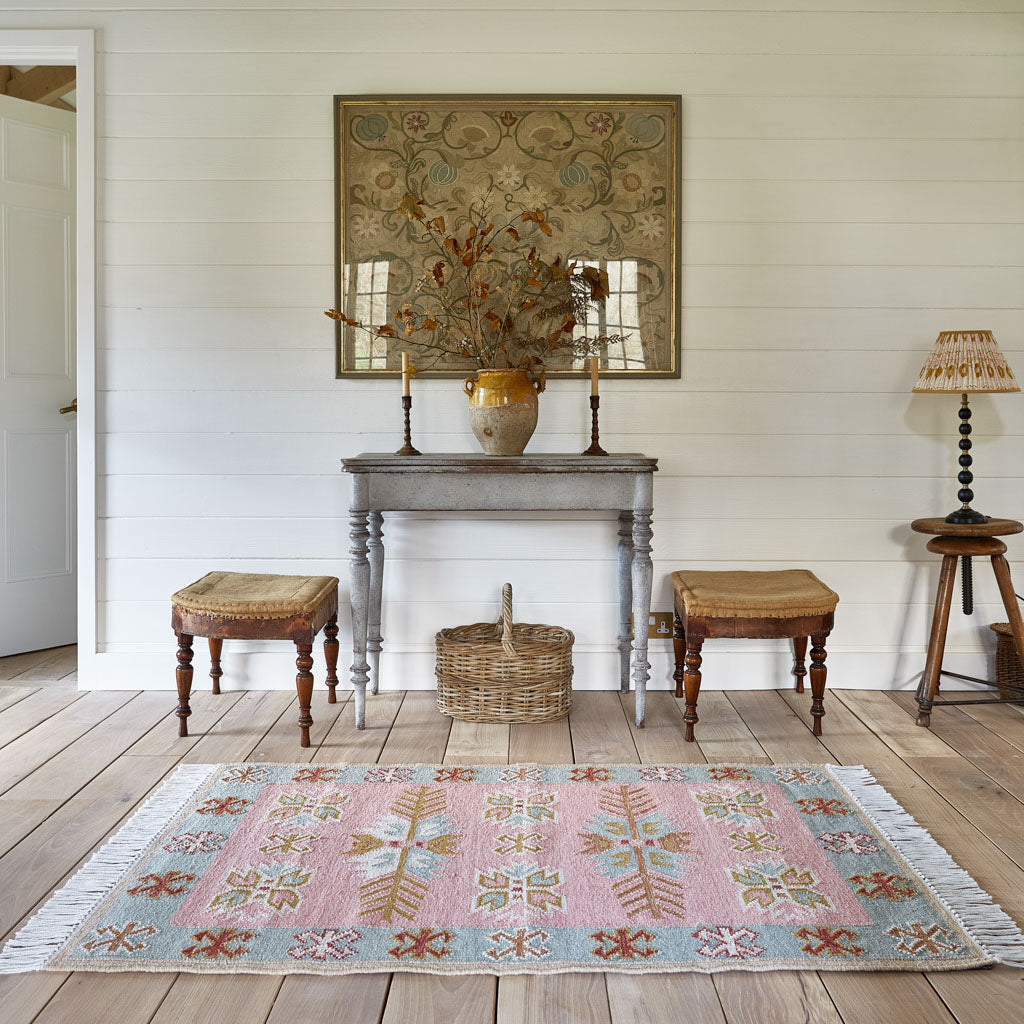 A pink, pale blue and neutral coloured rug in a hallway