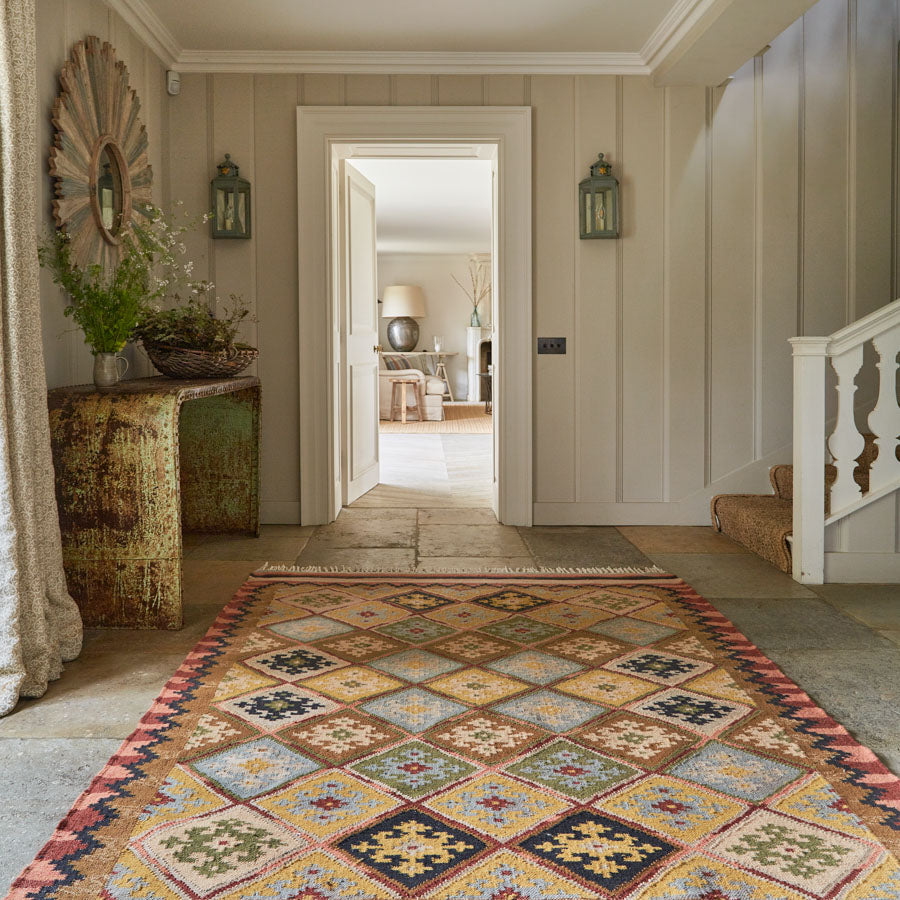Geometric patterned rug in neutral brown, olive and yellow tones in a hallway