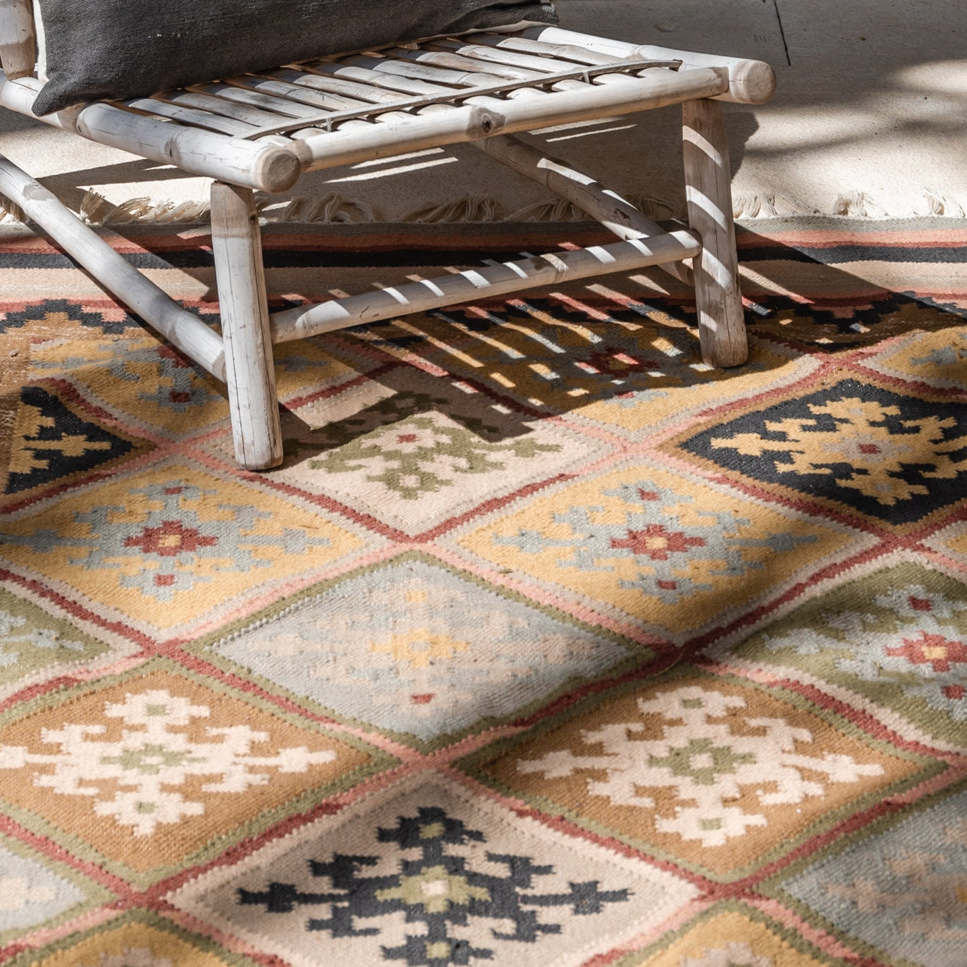 Decorative rug with geometric patterns in a room with a chair and plant.