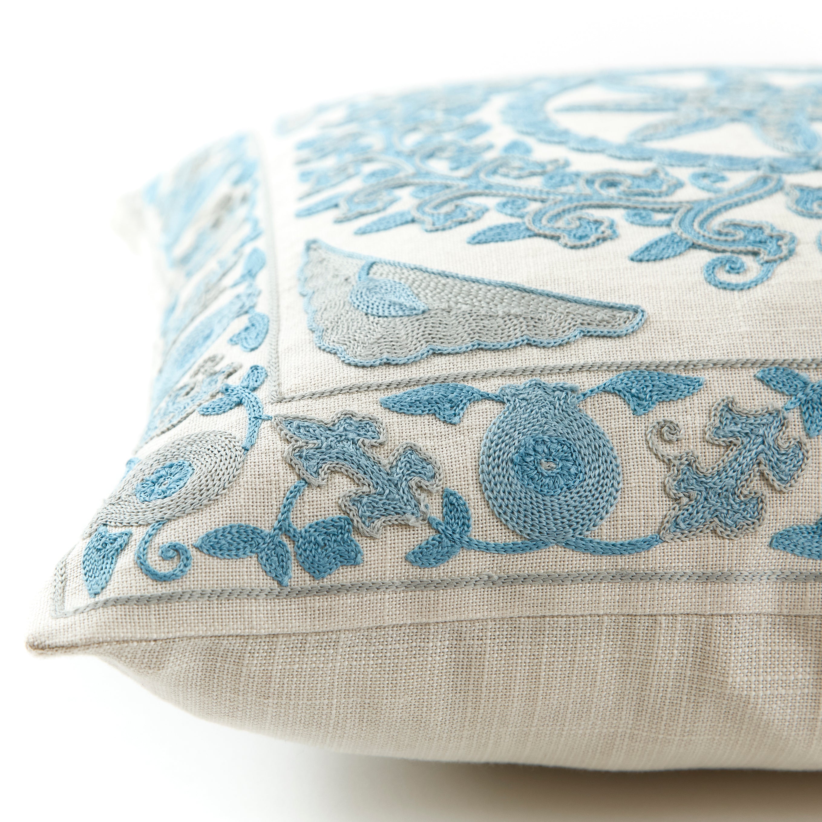 Blue embroidered cushion with a floral geometric pattern placed on a white background.