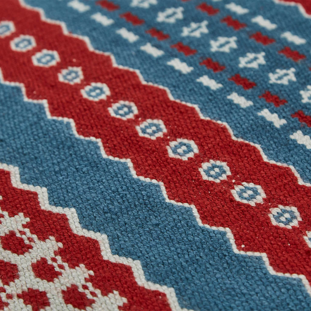 A red and blue striped rug with a geometric pattern