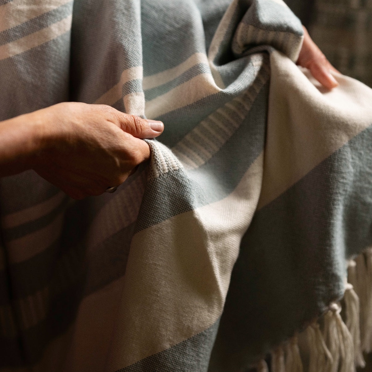 Person holding a striped Moli Sky Blue throw blanket with blue coluors.