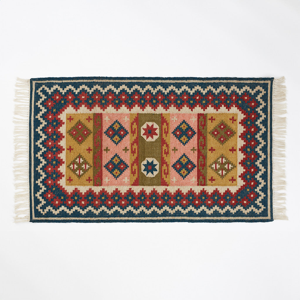 Geometric patterned rug in blue pink red and olive colourways