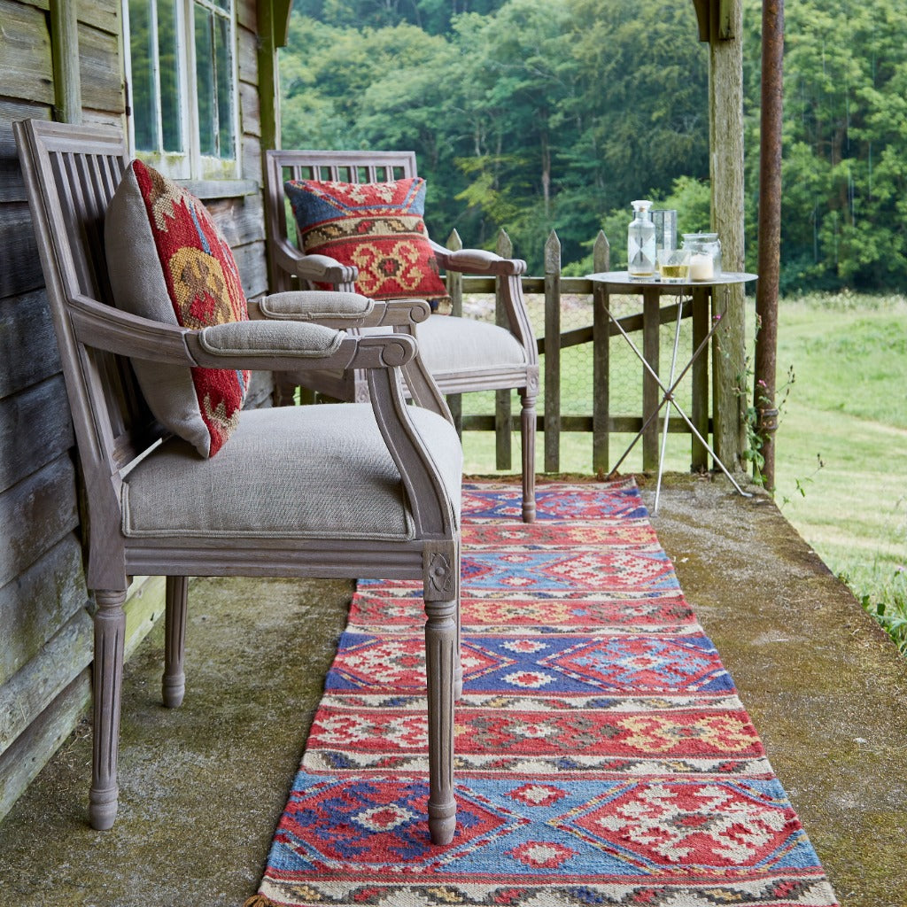 Outdoor setting with chairs and a colorful rug on a wooden deck.