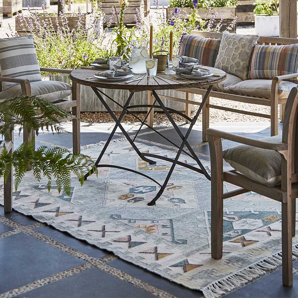 Garden furniture set up on patio with an outdoor rug cushions and throws