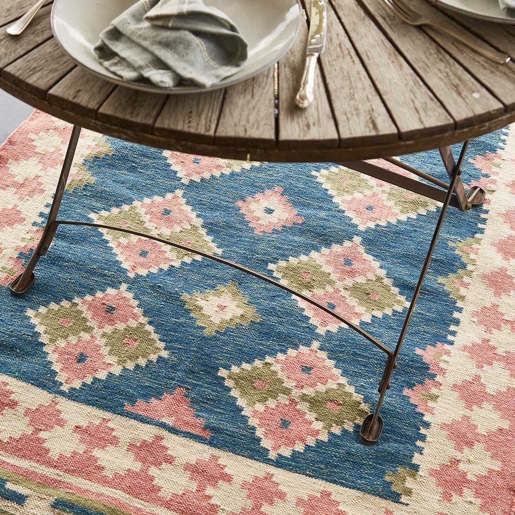 a plaster pink and dark blue geometric rug  under a table